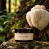 Lion's Mane extrakt från Aromexperten i mörk glasburk framför Lion’s Mane-svamp i naturlig skogsmiljö.